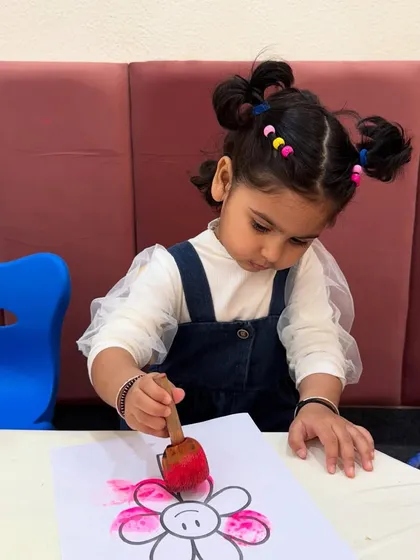 Involving children is the best way for them to learn. This little girl is happily engaged in a flower stamping activity, a simple yet effective way to develop her fine motor skills and creativity.