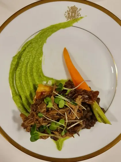 Pulled lamb with a pea puree and microgreens, served on elegant gold-rimmed china. For our sit-down dinners, we can arrange for premium crockery and glassware to elevate the experience.