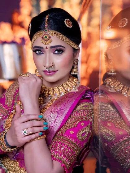 A powerful and direct portrait of a Telugu bride, with her reflection visible. The makeup is sharp and defined.