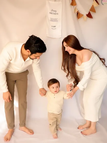A heartwarming family portrait where parents help their son take his first steps during his first birthday photoshoot. This photo beautifully combines a milestone moment with family connection.
