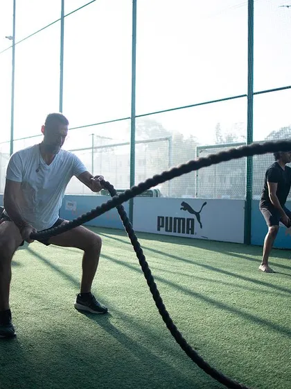 Two members using battle ropes with intense focus. This shows that our workouts incorporate modern functional tools alongside traditional ones for a comprehensive, high-intensity session.