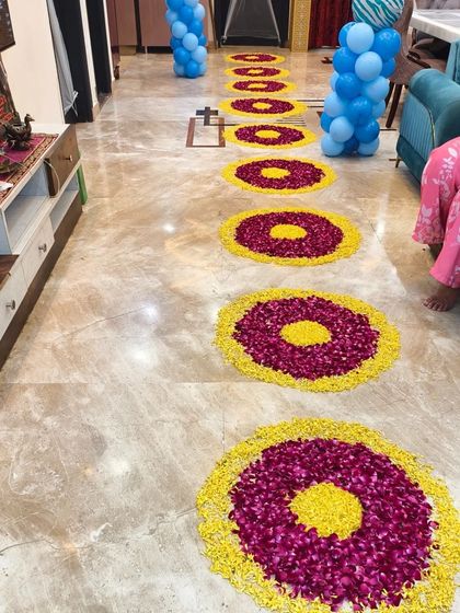 A pathway inside the home decorated with floral rangoli made from marigold and rose petals, leading to the main celebration area.