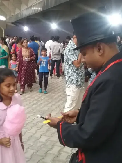 A close-up shot of my roving magic in action at a large public event. This young spectator is watching intently as I perform a trick just for her, creating a special, personal memory.