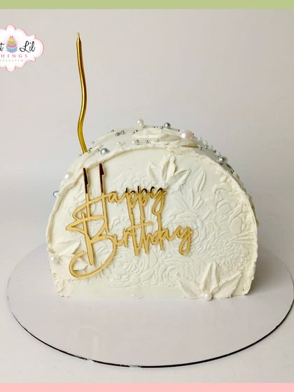An elegant and modern arch-shaped cake. This minimalist white design features a subtle texture and a single, statement gold candle.