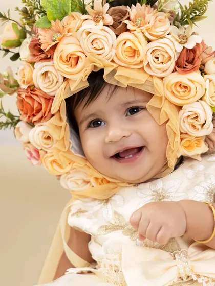 A close-up on a radiant smile. This beautiful portrait highlights the intricate floral bonnet and, most importantly, the pure happiness on this little girl's face.