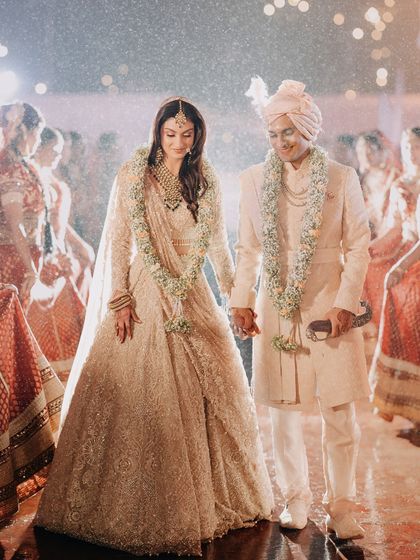 Abhishek and Raashi hold hands during their wedding ceremony. This image captures the solemnity and beauty of the ritual, focusing on the physical connection that symbolizes their union.