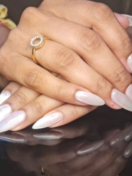A beautiful set of long stiletto nails with a pearly, off-white finish.