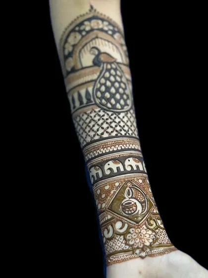 This design combines a peacock with an elephant procession and a diya. Learning to tell a story by combining different cultural symbols is part of the advanced bridal course.