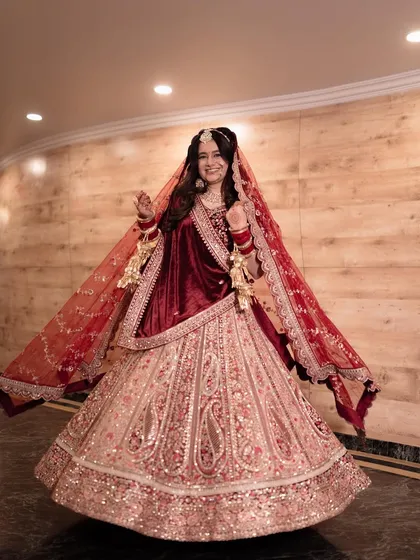 Capturing the joy of a wedding day is essential. This full-length shot shows the bride's beautiful velvet and embroidered lehenga in its entirety, while her happy twirl brings a sense of movement and celebration to the portrait.