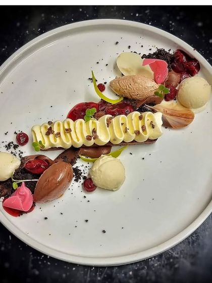 A deconstructed dessert plate. This artistic creation features different elements like chocolate mousse, ice cream, cake crumble, and fruit coulis, offering a variety of textures and flavors.