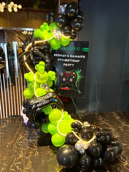 The entrance to the gaming party, featuring a personalized welcome sign and an explosive balloon arrangement in neon green and black. This setup immediately immerses guests in the "Game On" theme from the moment they arrive.