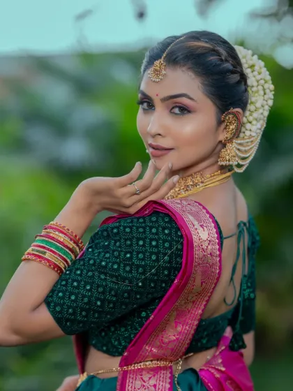 This side-back view shows how the hairstyle, makeup, and blouse design all work together. The soft braid is adorned with jasmine, complementing the traditional South Indian bridal look.