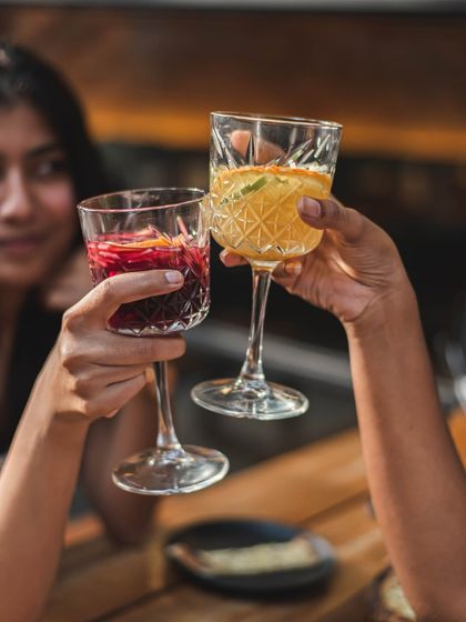 A close-up of two friends toasting with colorful mocktails, capturing a moment of connection.