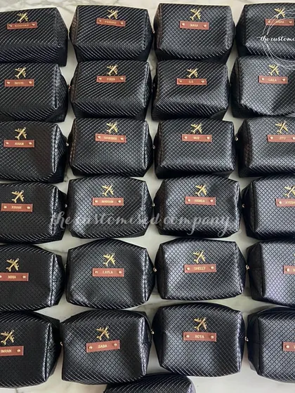 Make memories all over the world with our custom travel essentials. This image shows a large order of personalized black toiletry bags for a travel-themed event.
