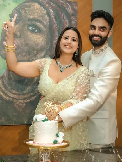 A joyous cake-cutting moment during an indoor engagement celebration in Pune. The couple's happiness is the focus, framed by modern decor and a beautiful piece of art, capturing the celebratory spirit of the occasion.