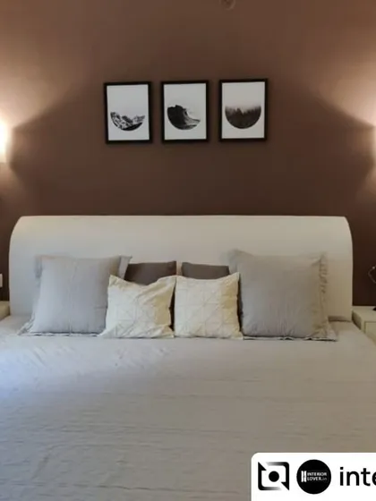 A simple and serene guest bedroom. The design uses a muted color palette with a deep brown accent wall and elegant wall sconces to create a warm and welcoming space for visitors.
