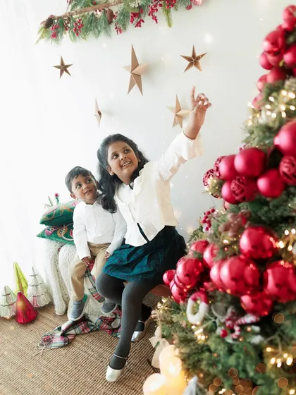 A big sister acts as a compass, guiding her little brother to the magic of Christmas. This candid moment from a festive mini-session perfectly captures their sweet sibling love.