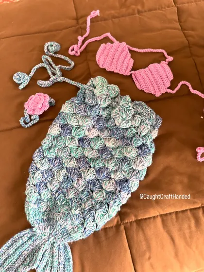 The complete mermaid photoshoot set laid out. You can see the beautiful scale-like stitch on the tail and the matching shell top and floral headband. It's a dream outfit for any baby's first photos.