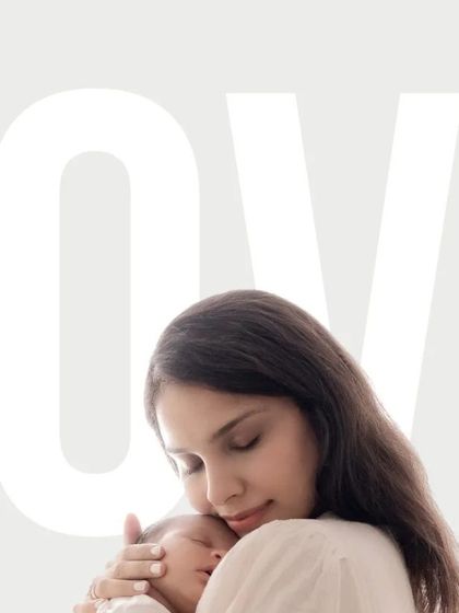 A mother holds her sleeping newborn close to her heart. The word "LOVE" overlaid on the image perfectly describes this profound, peaceful moment.