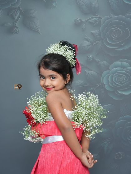 A girl in a creative floral dress looks over her shoulder with a sweet smile. The artistic floral background adds another layer of beauty to this portrait.