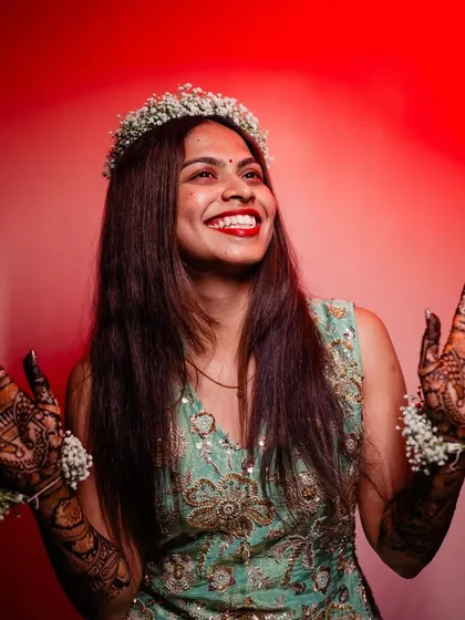 A joyful bride with her hands up, showing off her beautiful mehendi.