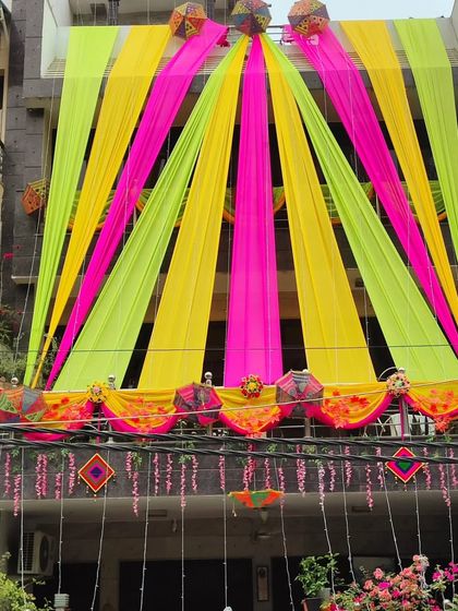 A beautiful house front decorated in lime green, yellow, and pink, with hanging floral elements and traditional accents.