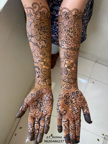 Another view of Arfa's bridal henna, highlighting the intricate floral work on the palms and the detailed checkerboard patterns on the fingers.