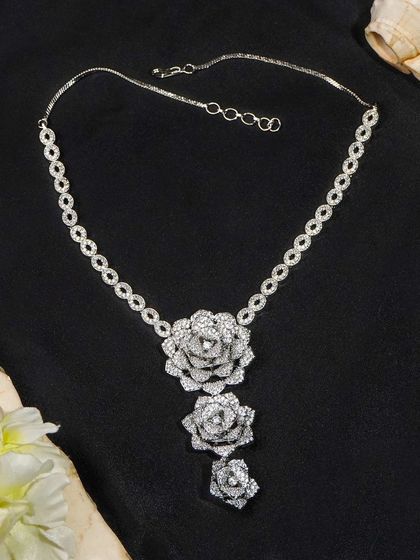 A stunning diamond floral necklace styled against a black background with soft props. This type of dramatic shot is perfect for website banners and promotional materials.