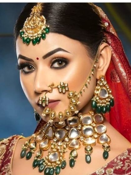 A classic bridal look with a heavy Kundan and emerald necklace. The red dupatta and bindi complete the traditional Indian bride aesthetic.