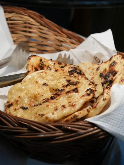 A basket of soft, freshly made naan, still warm from the tandoor. The perfect accompaniment to our flavorful Indian curries.