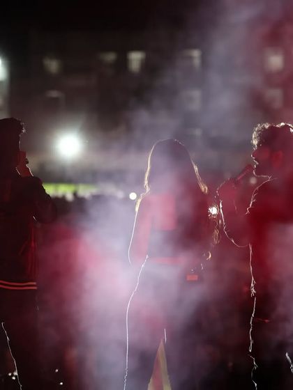 A silhouette of the artists on stage, creating a dramatic visual against the backdrop of stage smoke and lights.