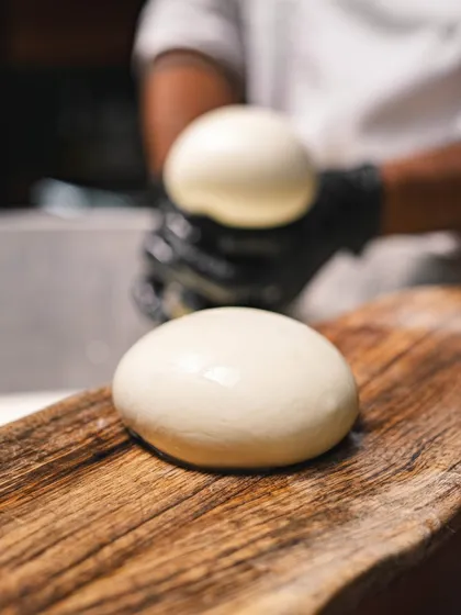 Two perfect balls of our handmade mozzarella, smooth and supple, resting on a wooden board before being used or packaged.