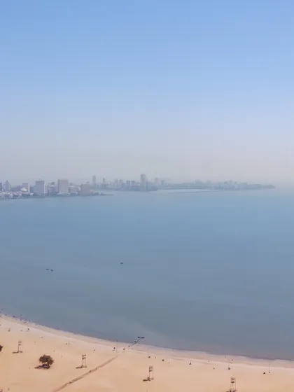 A drone's view of Chowpatty Beach and the vast expanse of the Arabian Sea, with the distant Mumbai skyline visible on the horizon.