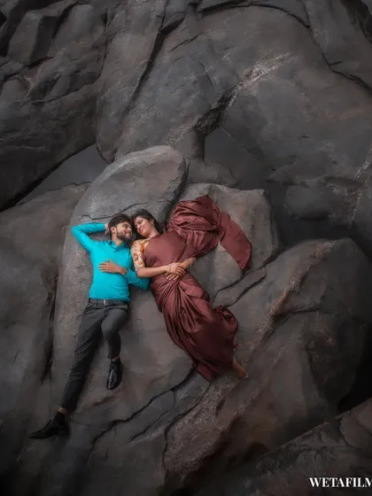 An artistic overhead shot of a couple nestled among dramatic rock formations. We look for unique angles and textures in nature to create visually striking and memorable pre-wedding portraits.