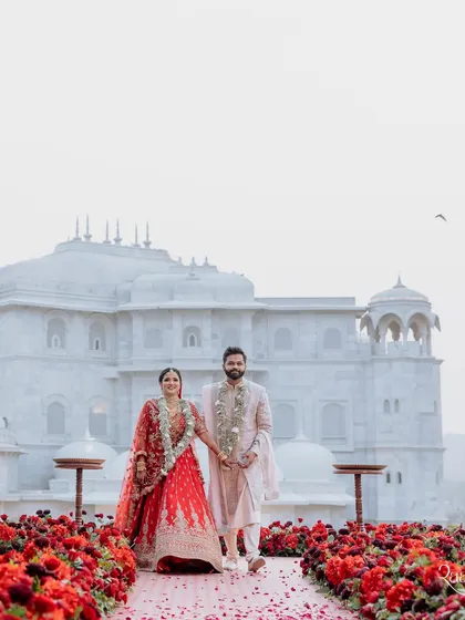 The couple's walk after the ceremony, with the stunning white architecture of the Fairmont Jaipur in the background. The aisle, lined with red roses, provided a beautiful contrast.