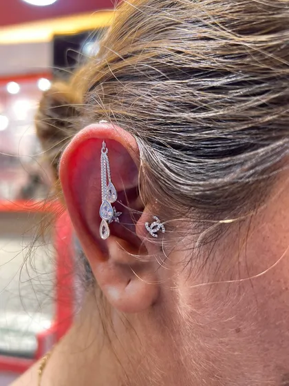 A delicate and graceful ear curation. This look features a long, dangling silver hanging paired with a classic logo stud for a touch of modern elegance.