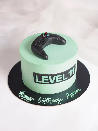Level 11 unlocked! A cool gamer-themed cake in a mint green color. It's topped with a handmade, edible game controller, making it the perfect cake for a young gamer's birthday.