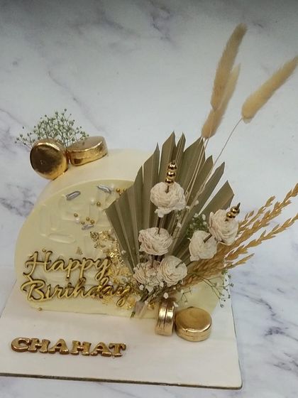 This unique half-cake design is perfect for smaller, yet equally stylish, celebrations. We decorated it with dried botanicals, macarons, and gold accents for a chic and modern look.