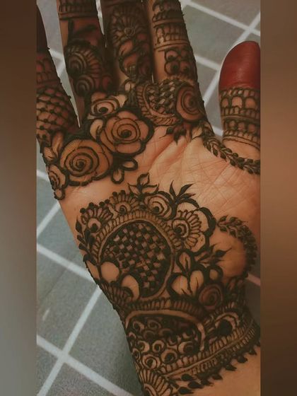 A close-up of the palm from the previous bridal design, showing the rich stain on the delicate rose and checkerboard patterns.