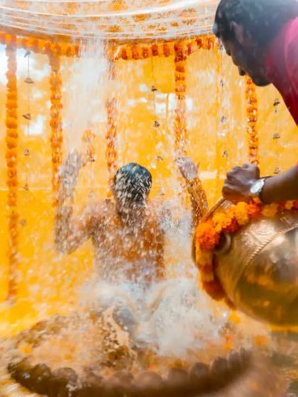 An energetic shot capturing the groom being drenched with water during a fun-filled Haldi ceremony.