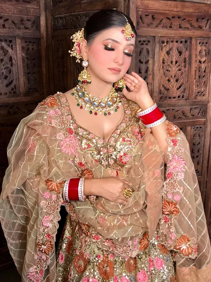 A full-length shot of the bride, showing her stunning gold lehenga and heavy kundan jewelry.