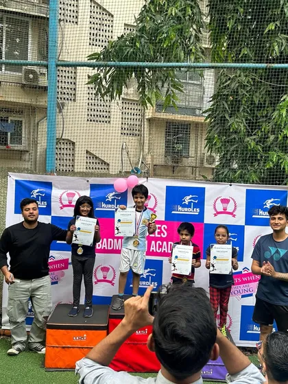 The joy of achievement is a huge part of our community. Here, young champions celebrate on the podium at our badminton tournament, proudly holding their certificates and medals, surrounded by coaches and family.