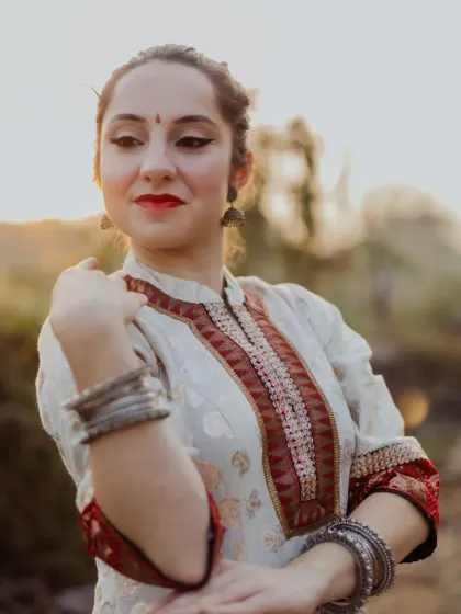 A beautiful close-up portrait of the Kathak dancer. The warm, golden hour light softly illuminates her face, highlighting her expressive features and traditional makeup.