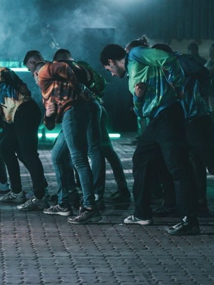 The dancers in a powerful, athletic stance. The performance showcases the physicality and raw energy of post-internet dance styles like jumpstyle.