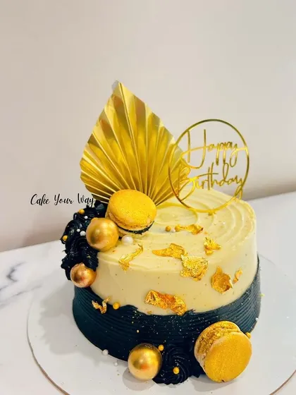 Gracefully crafted, exquisitely delicious. A modern black, white, and gold cake with macarons.