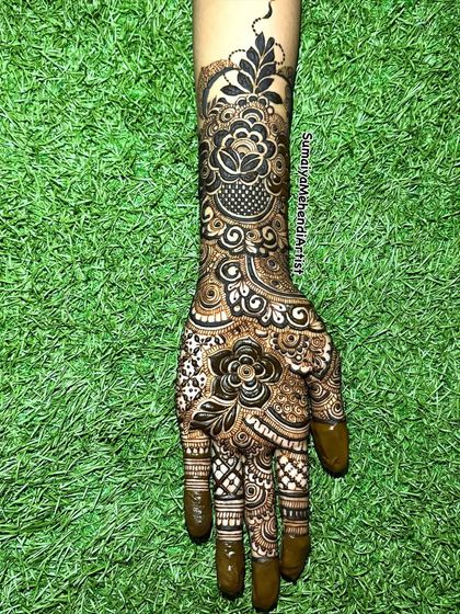This shot against the green grass really makes the dark henna paste pop. A beautiful floral design for any occasion.