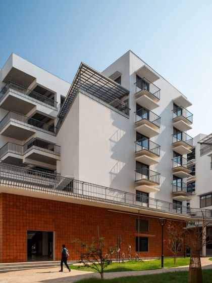 The facade of a building at the Srishti campus, showing staggered balconies and varied window openings. This approach breaks the monotony of the facade and creates a dynamic visual rhythm.