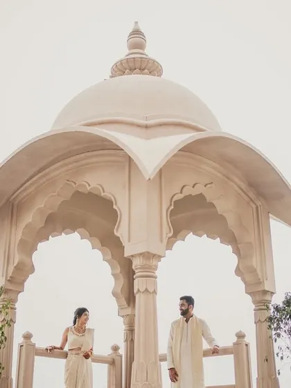 The couple posing under a beautiful Rajasthani-style dome at their Jaipur wedding venue.