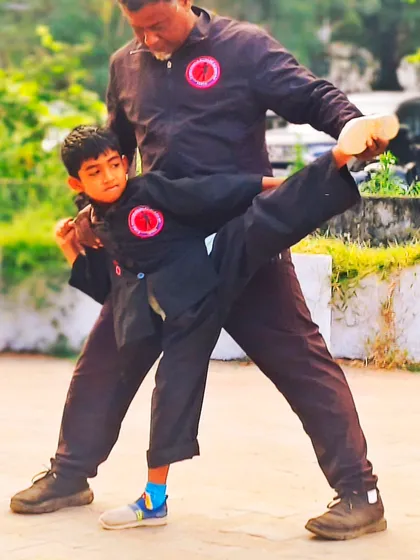 Guiding a young student in a supported side kick. Personal attention is key to helping children learn complex movements safely and correctly.