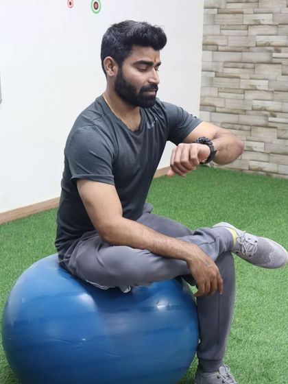 Taking a moment to check my watch while seated on a stability ball. This tool is great for engaging the core muscles even while resting, promoting active sitting.